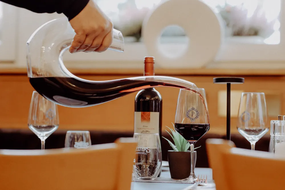 Red wine being poured from a carafe at a set table